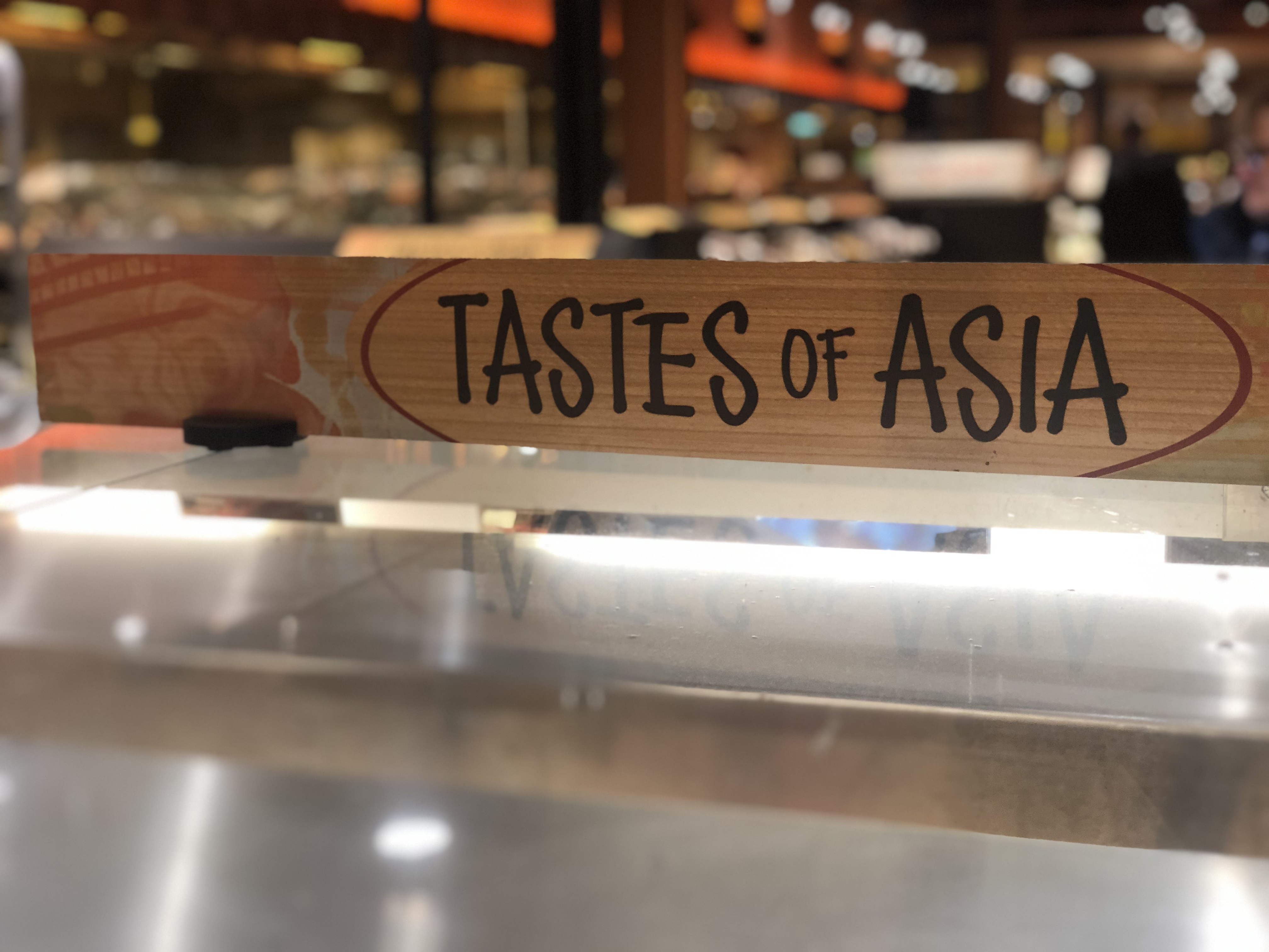 Image of 'Tastes of Asia' sign with blurred grocery store background.